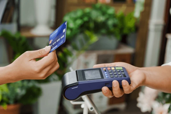Customer paying contactlessly on a card terminal, illustrating merchant services.