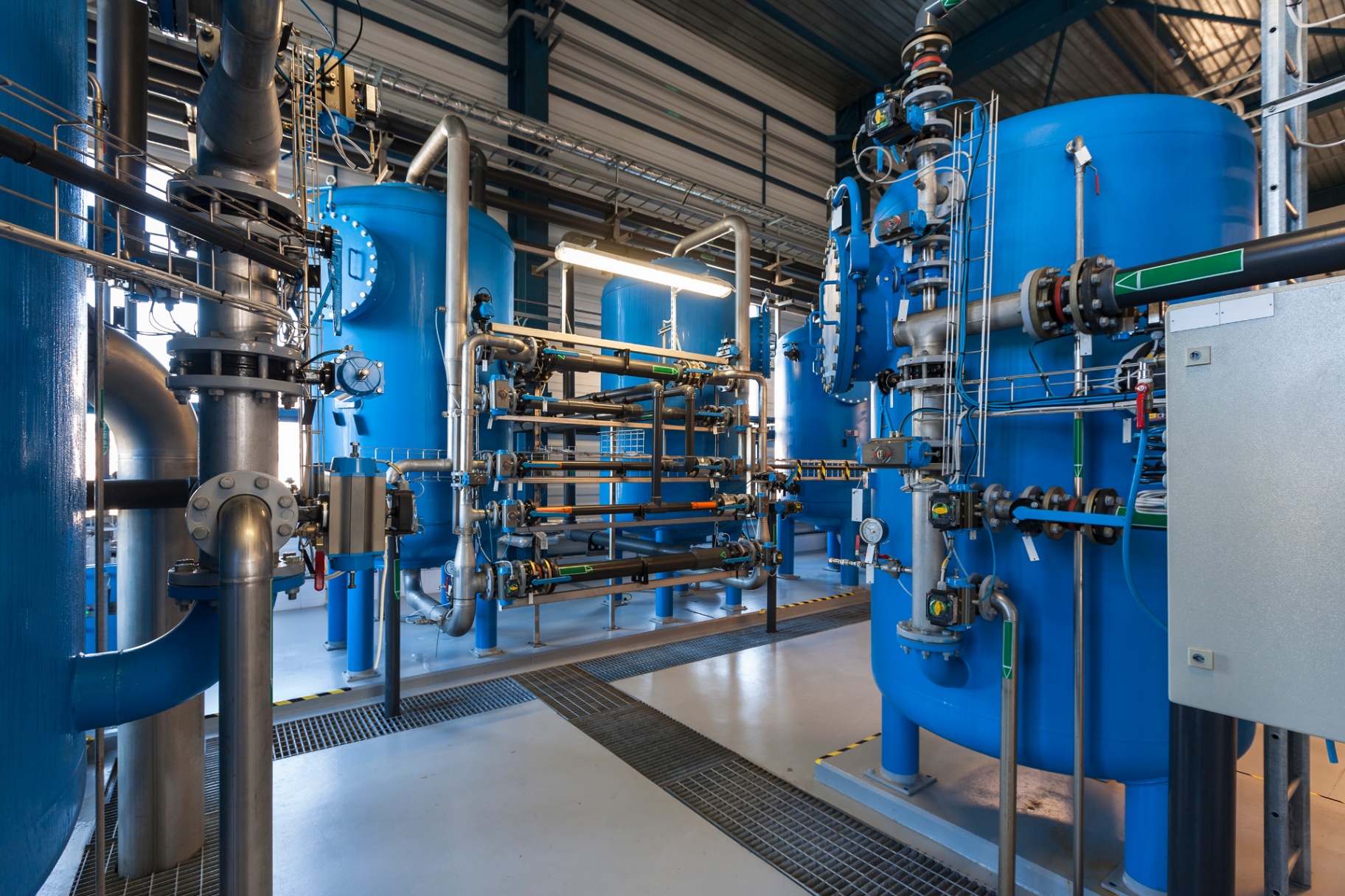 Industrial water treatment plant with blue pressure vessels and pipework, illustrating commercial water services.